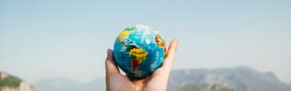 Person holding world globe in hand (photo: Porapak Apichodilok/Pexels)